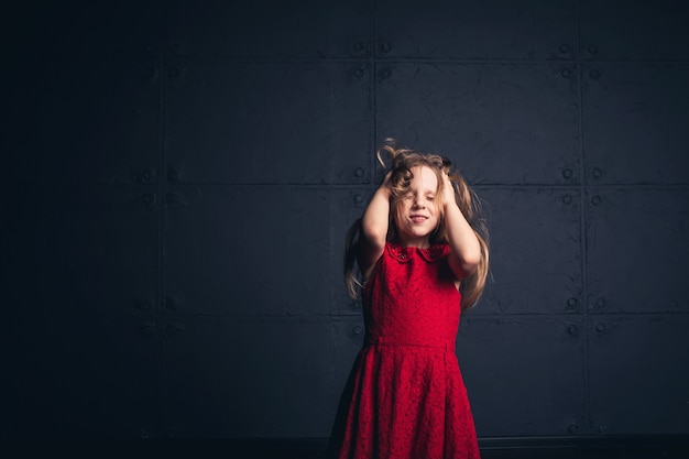 Meisje in rode jurk heft haar haar met haar handen op en sluit haar ogen