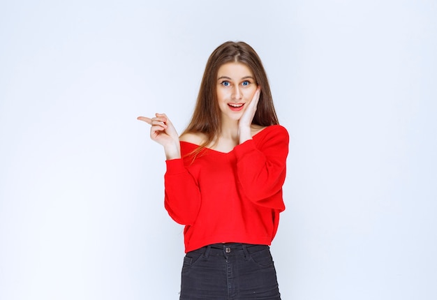 Meisje in rood shirt met iets aan de linkerkant.