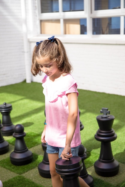 Meisje in roze t-shirt op een gigantisch schaakbord op haar school.