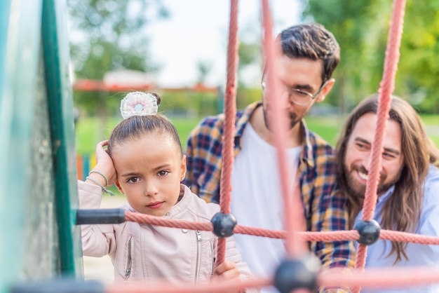 Meisje in speelplaats met haar ouders die ongelukkig naar de camera kijken.