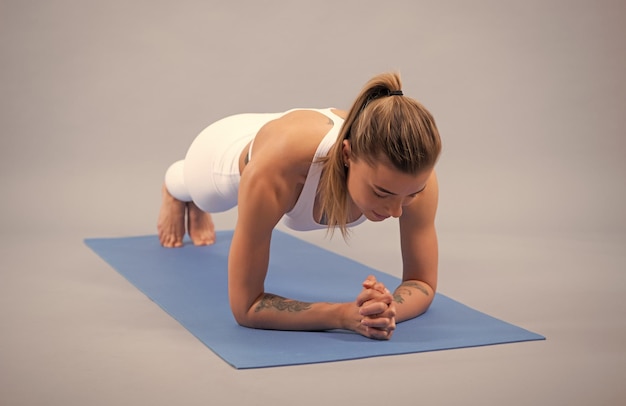 Meisje in sportkleding die in plank staat voor kernspieren op fitnessmattraining