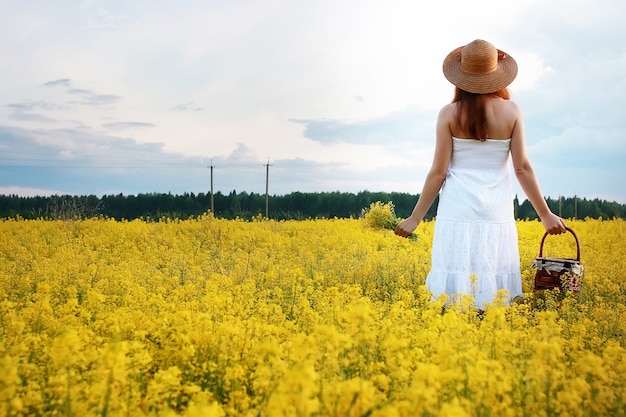 Meisje in strohoed op gebied van gele bloemen die bloeien