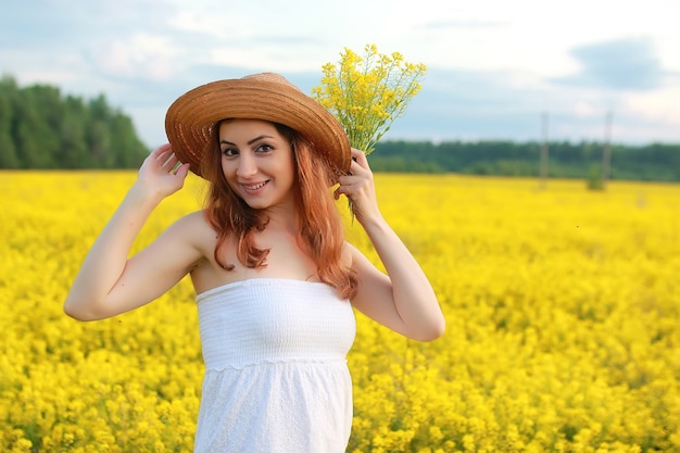 Meisje in strohoed op gebied van gele bloemen die bloeien