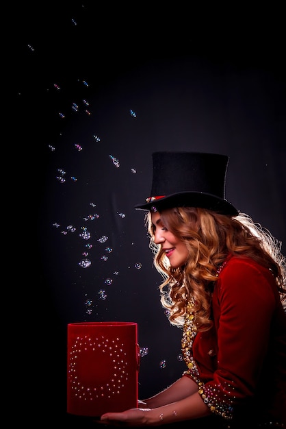 Foto meisje in toneelkostuum en hoge hoed op haar hoofd. vrouwelijke goochelaar, een illusionist in theatrale kleding