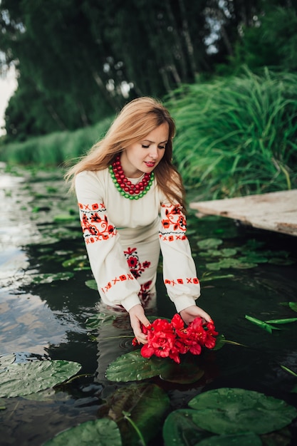 meisje in traditionele Oekraïense kleren brengen bloem krans in het water