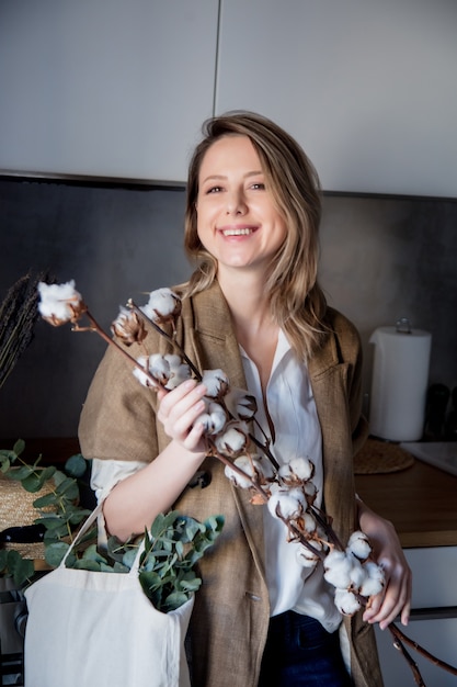 Meisje in vest met draagtas en katoenplant in een keuken