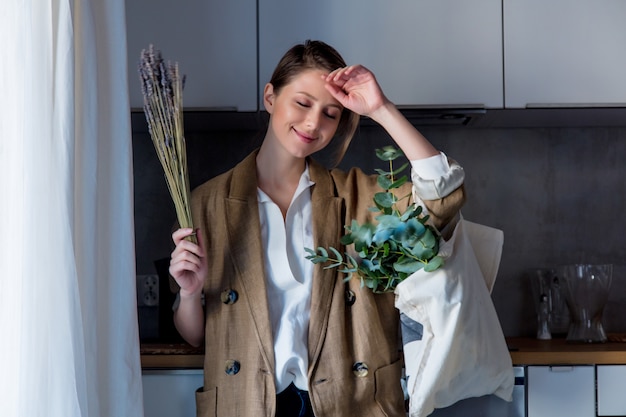 Meisje in vest met draagtas en planten in een keuken