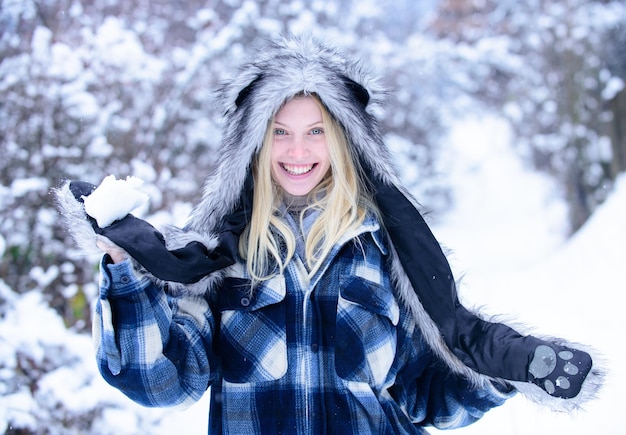 Meisje in wanten houdt sneeuwbal vast Meisje speelt met sneeuw lachende vrouw in warme kleding met sneeuwbal