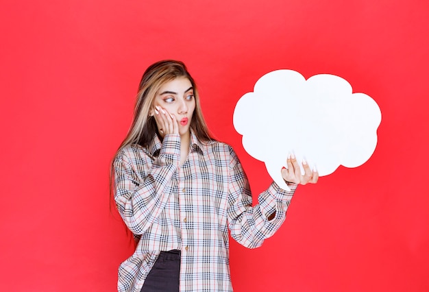 Meisje in warme trui met een ideebord in de vorm van een wolk en kijkt verrast