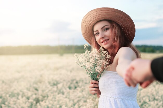 Meisje in witte jurk in het veld met gele bloemen in bloei