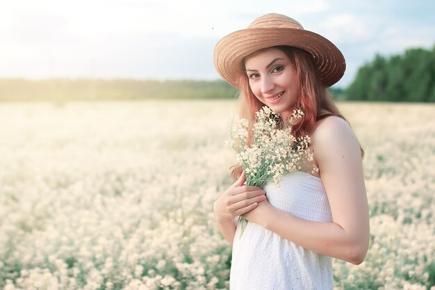 Meisje in witte jurk in het veld met gele bloemen in bloei