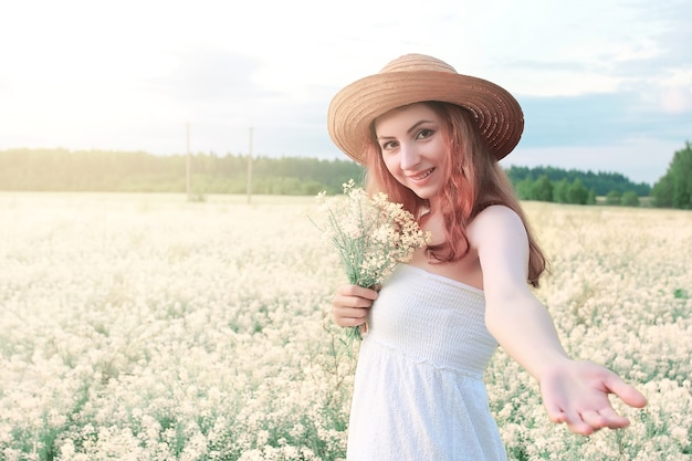 Meisje in witte jurk in het veld met gele bloemen in bloei