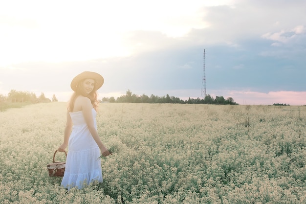 Meisje in witte jurk in het veld met gele bloemen in bloei