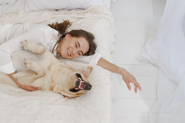 Meisje in witte kleren met hond labrador die thuis speelt