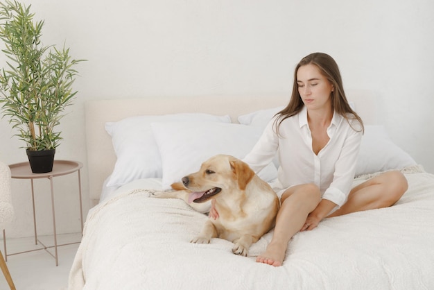 Meisje in witte kleren met hond labrador die thuis speelt