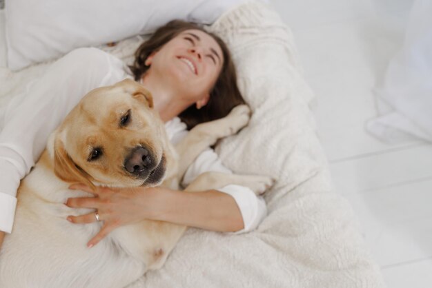 Meisje in witte kleren met hond labrador die thuis speelt