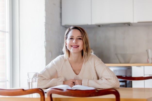 Meisje in witte sweater met boekzitting bij lijst