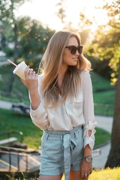 Meisje in zonnebril die een milkshake drinkt en glimlacht