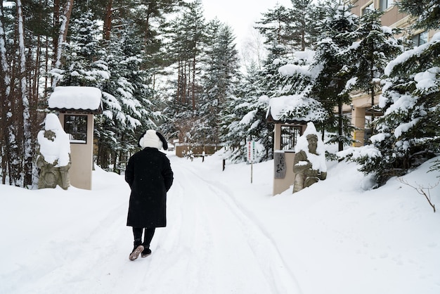 Foto meisje in zwarte jas lopen in sneeuwbos