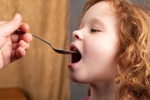 Meisje jaar oud drinkt hoestsiroop van een spoonthe kind neemt medicatie close-up