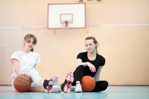 Meisje jonge student in de sportschool die een basketbal speelt