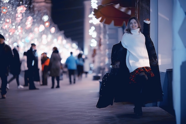 meisje kerstverlichting 's avonds versierde stad, een jong model op de achtergrond van stedelijke decoraties en slingers, nacht stadslichten