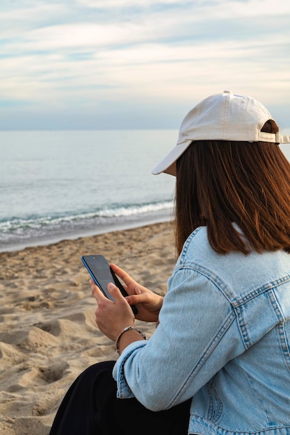 Meisje kijkt naar haar mobiele telefoon op het strand.