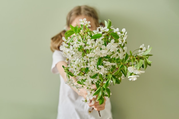 Meisje kind geeft lente witte bloemen bloeiende kersen takken