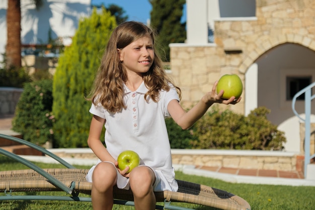 Meisje kind gooien, spelen, jongleren met groene appels, zonnige zomerdag