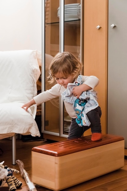 Meisje klimt op een houten doos thuis.