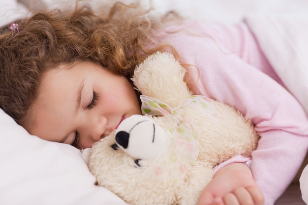 Meisje knuffelen haar teddy tijdens het slapen