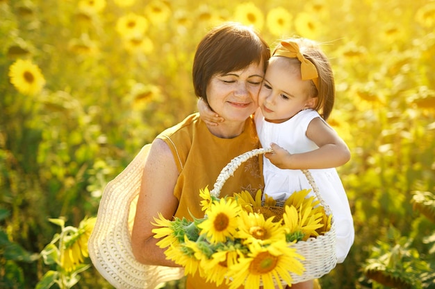 Meisje knuffelt haar grootmoeder met een mand met zonnebloemen in de hand Grootoudersdag