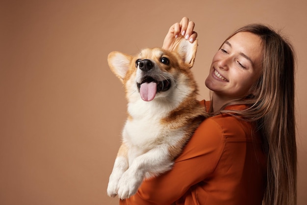 Meisje knuffelt Pembroke Welsh Corgi op een beige schone achtergrond in de studio liefde voor dieren