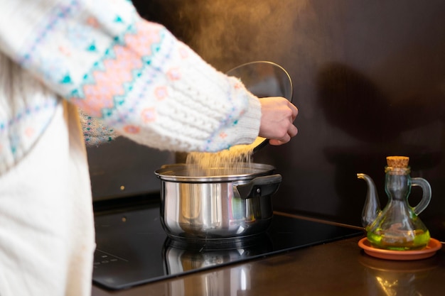 Meisje kokend meisje dat de rijst in het kokende water doet