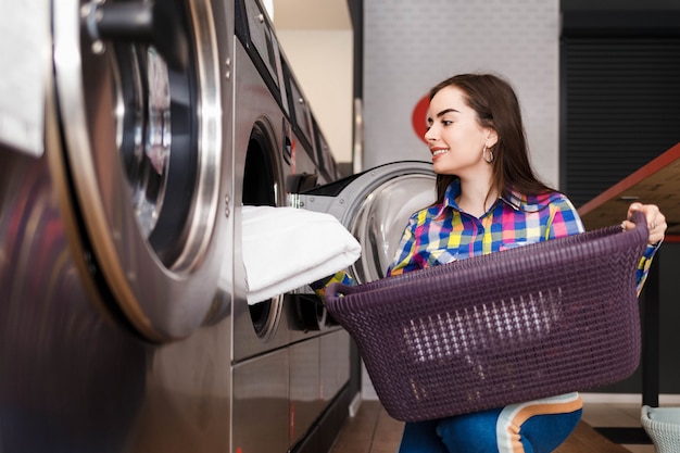 Meisje laadt wasgoed in een wasmachine. vrouw in openbare wasserette