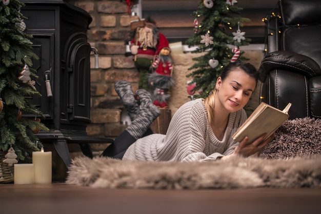 meisje leest een boek in een gezellige huiselijke sfeer bij de open haard