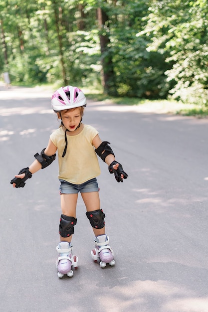 Meisje leren rolschaatsen. Kid meisje in beschermende sportkleding