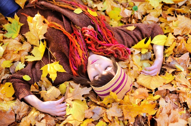 Meisje liggend in het portret van de herfstbladeren.