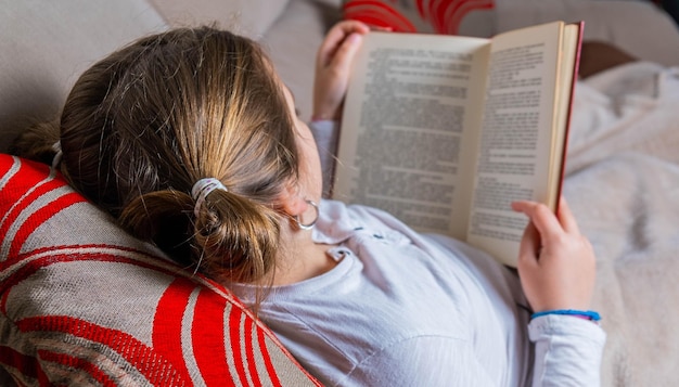 Meisje liggend op de bank rustig een boek lezen Wereldboekendag Kindlezing Promotie Thuisleven