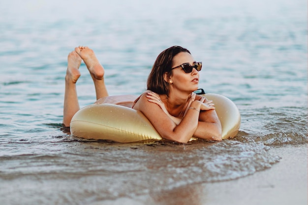 Meisje liggend op een gouden zwembuis op het strand