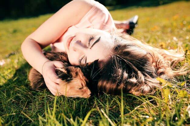 Meisje liggend op gras met kat. Lente of zomer warm weer concept.