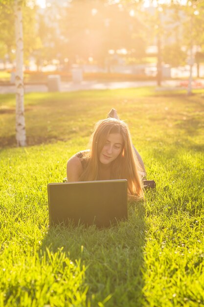 Meisje liggend op het gras met laptop