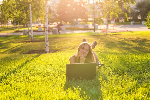 Meisje liggend op het gras met laptop