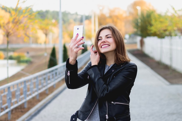 Meisje loopt in de herfst in het park en neemt een selfie