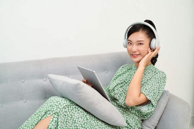 Meisje luisteren muziek online met een tablet zittend op een bank in de huiskamer