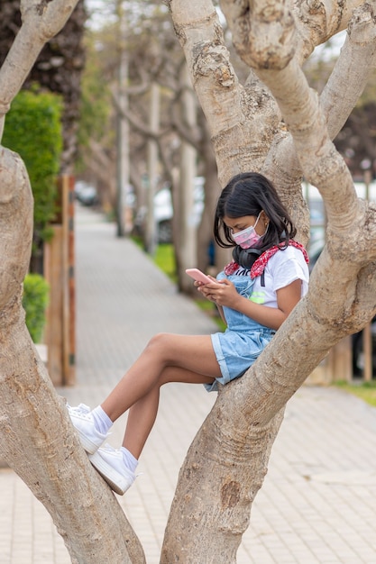 Meisje luistert naar muziek met haar koptelefoon op een boom