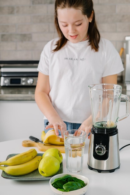 Foto meisje maakt een smoothie thuis.