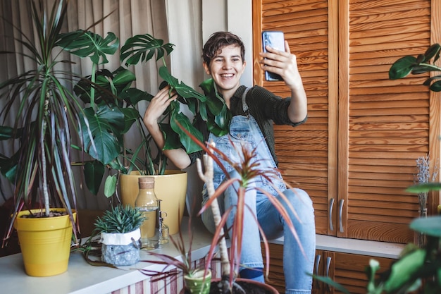 Meisje maakt foto met smartphone voor sociale media huisplanten op balkon groene kamer tuinieren