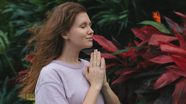 Meisje mediteert in een park in de natuur of bidt in een tropische tuin, ontspant in de natuur en ademt