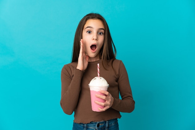 Meisje met aardbei milkshake geïsoleerd op blauwe muur met verrassing en geschokt gelaatsuitdrukking